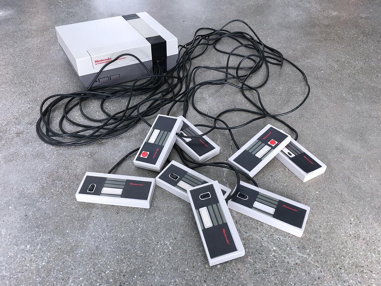 A photograph of the Octopad's eight one-switch controllers alongside a Nintendo Entertainment System.