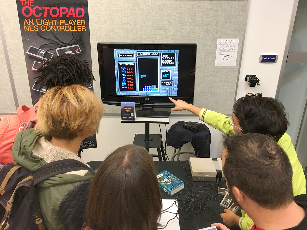 A group of people playing together and pointing at the screen at IndieCade 2018 at Santa Monica College.